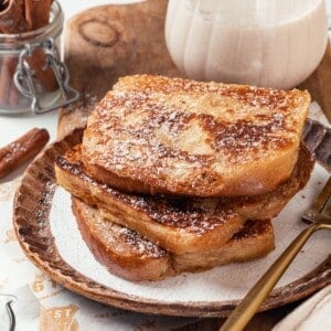 Stack of 3 slices of eggnog French toast on plate.