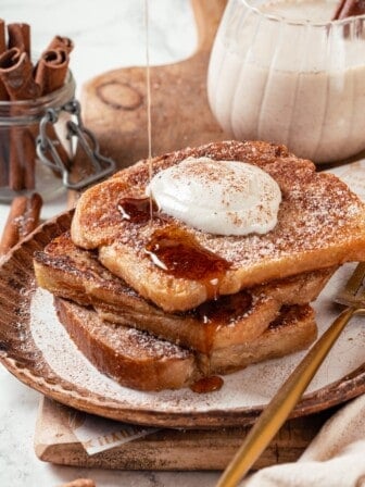 Drizzling syrup onto stack of vegan eggnog French toast.
