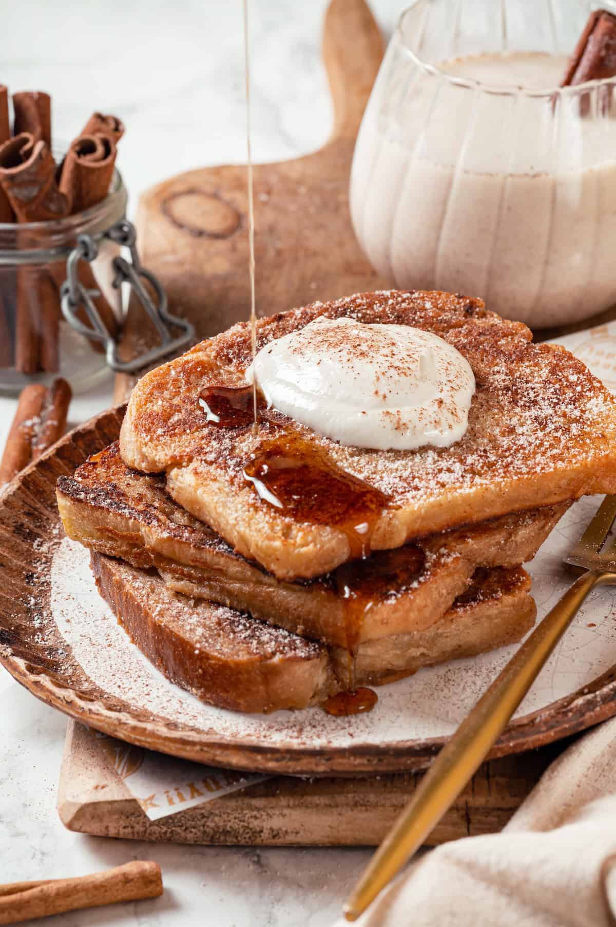 Drizzling syrup onto stack of vegan eggnog French toast.