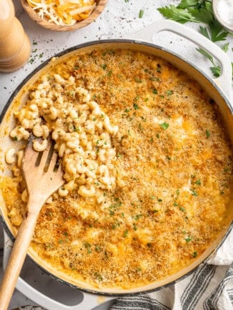Wooden spatula scooping vegan mac and cheese from skillet.