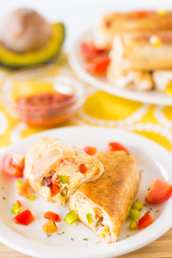 A mexican breakfast burrito cut in half on a white plate. 