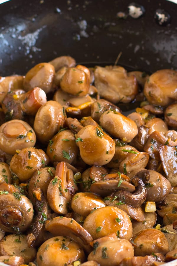 Top down shot of garlic sautéed mushrooms in a pan. 