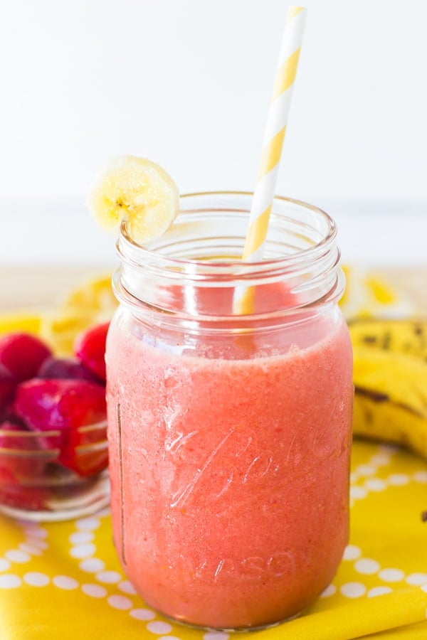 Strawberry banana smoothie in a glass mason jar with yellow straw.