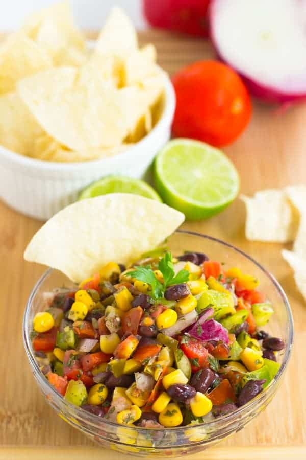 Black bean salsa in a glass bowl on a wood board. 