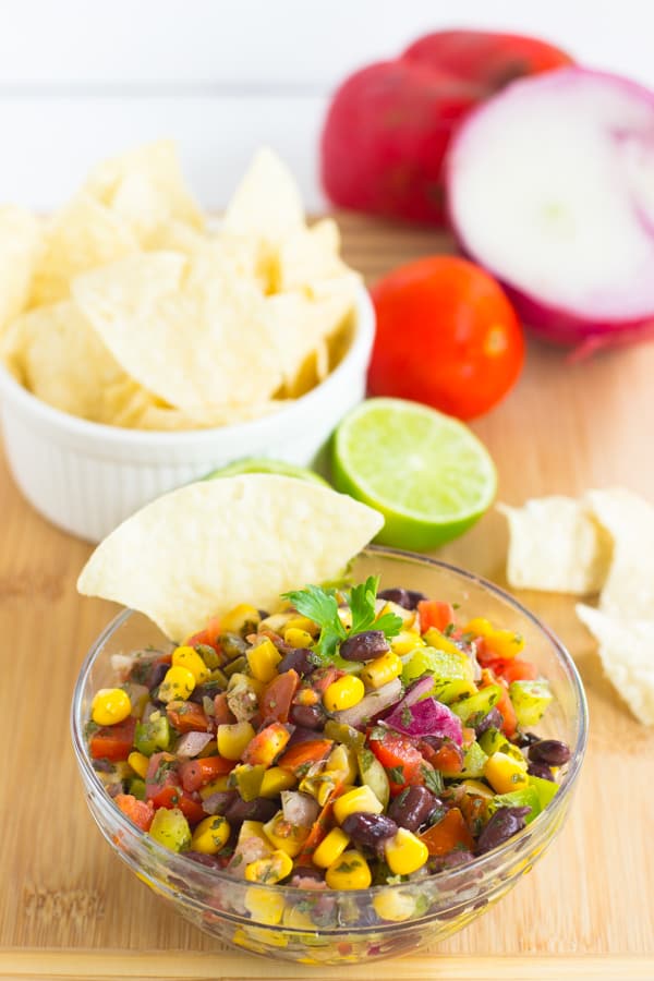 Black Bean Salsa in a glass bowl with a chip in it. 