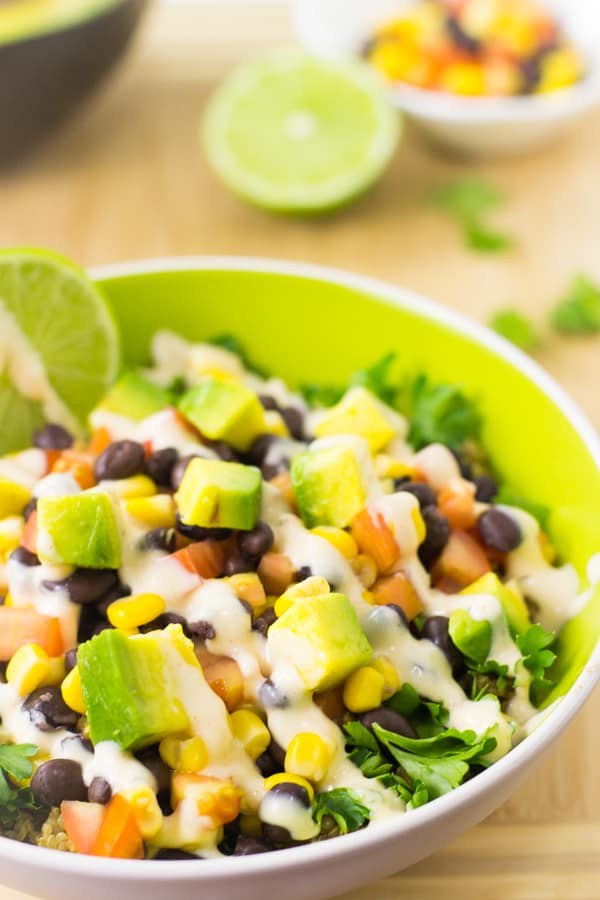 Close up of quinoa and black bean burrito bowl on a wood table.