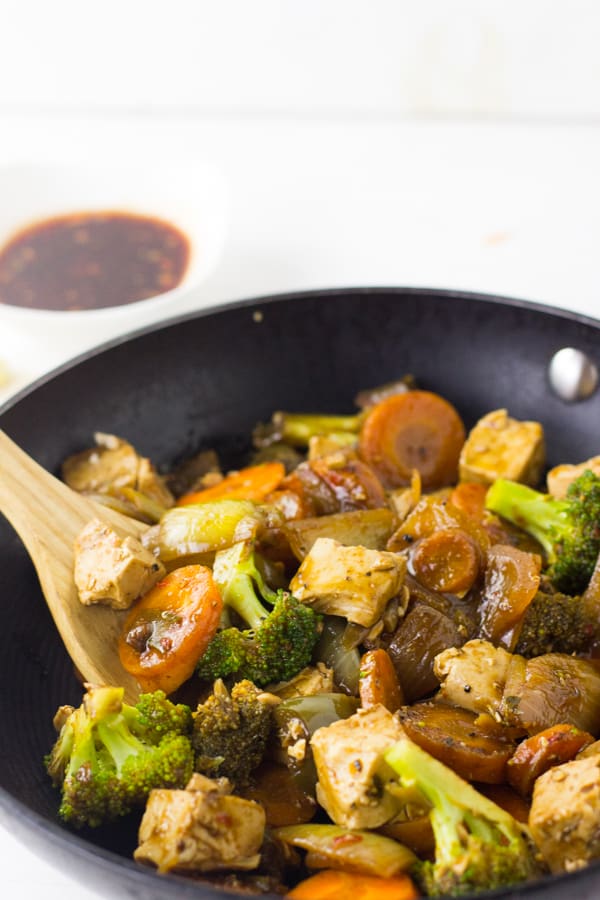 Stirring asian tofu stir fry with Honey Sriracha Sauce in a wok. 