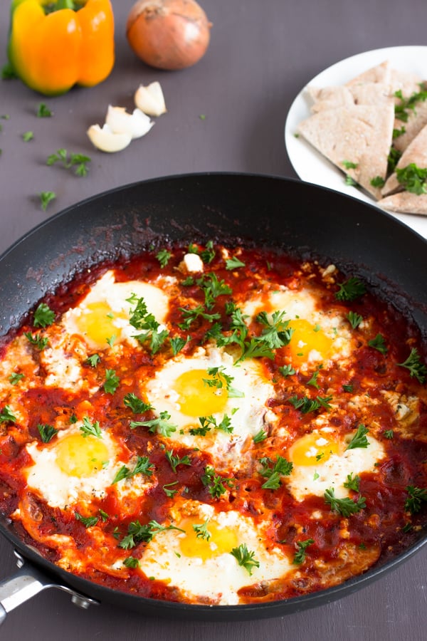 Spicy shakshuka with feta in a black skillet with pita slices on the side. 