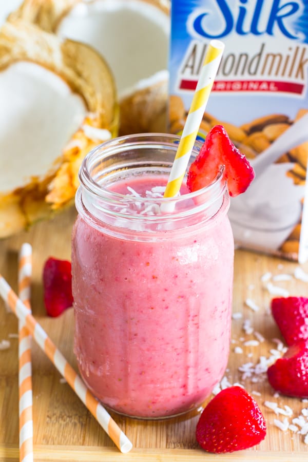 Strawberry coconut smoothie in a mason jar with a yellow striped straw. 