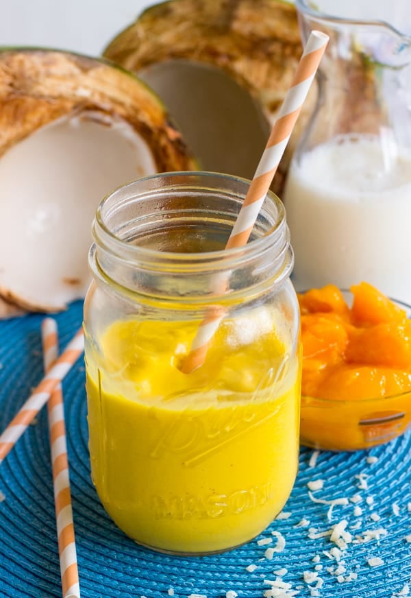 Mango coconut smoothie in a mason jar with a straw.
