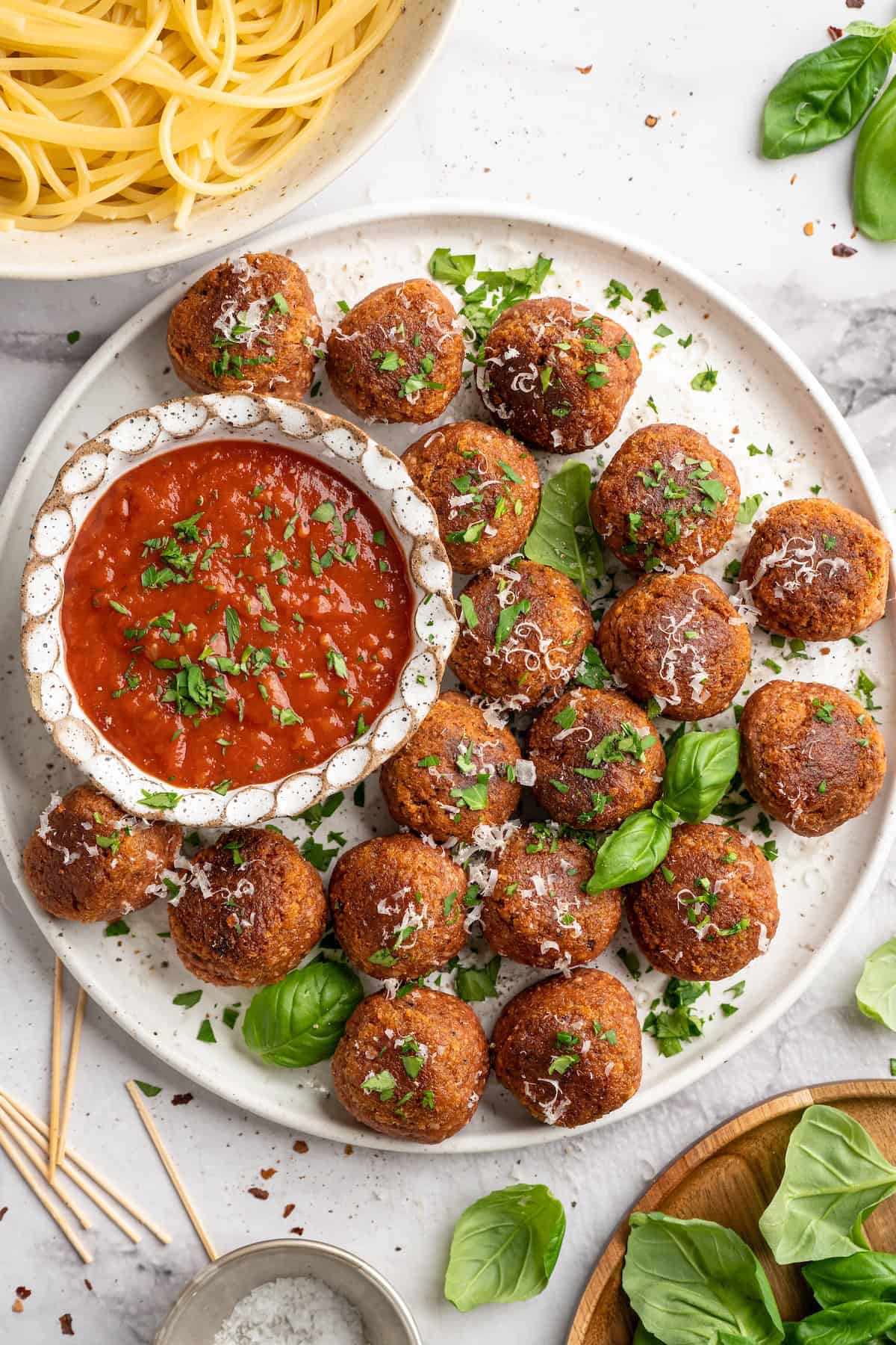 Overhead view of chickpea and beet vegetarian meatballs on platter with bowl of marinara