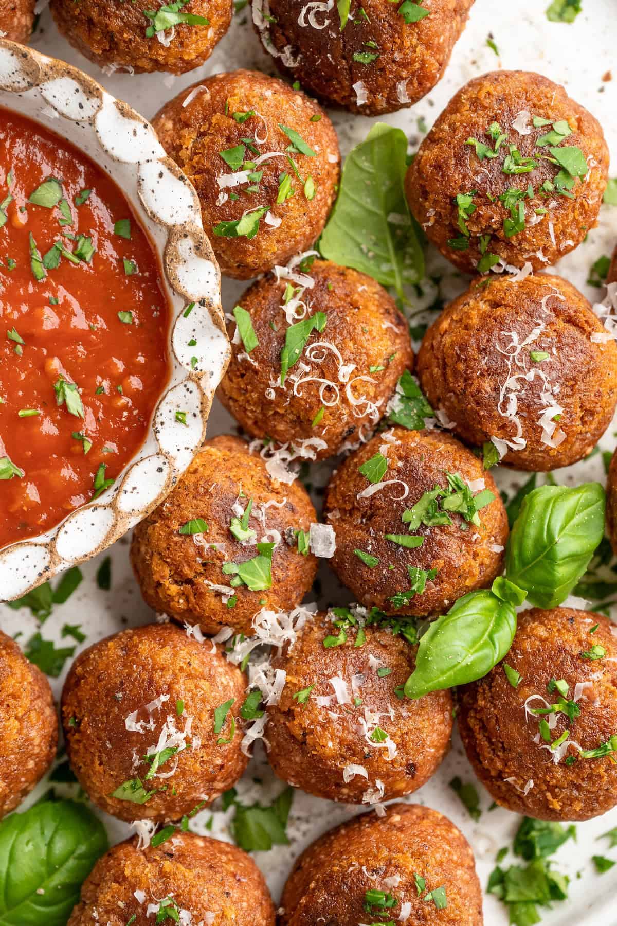 Overhead view of chickpea and beet vegetarian meatballs with bowl of marinara