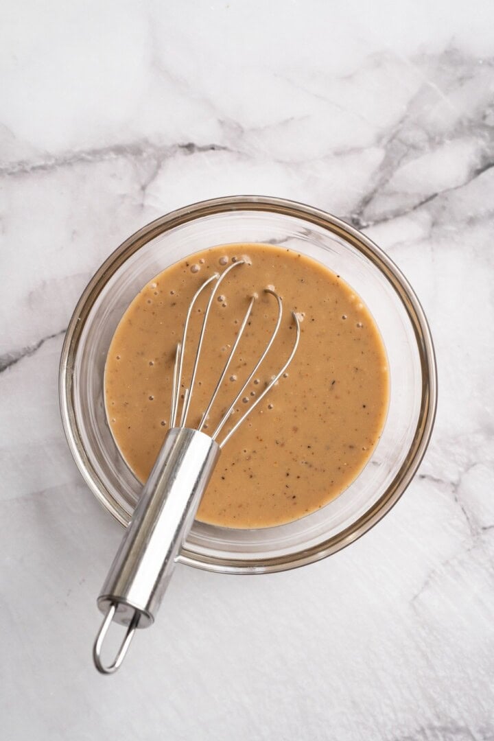This beet feta salad pairs tender roasted beets and tangy vegan feta, along with a zippy maple mustard vinaigrette. Delicious and easy! Overhead view of maple mustard vinaigrette in bowl with whisk