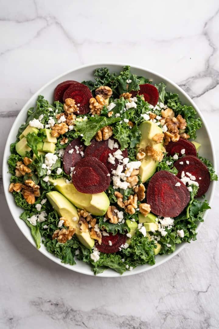 This beet feta salad pairs tender roasted beets and tangy vegan feta, along with a zippy maple mustard vinaigrette. Delicious and easy! Overhead view of beet feta salad in bowl before adding dressing