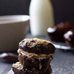 Side shot of chocolate donuts stacked on a table.