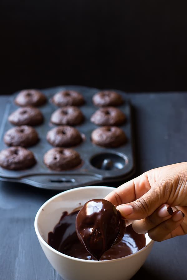 Hand dipping a donut in chocolate. 