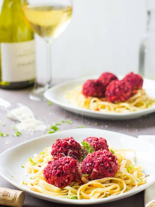  Chickpea and beet vegetarian meatballs with spaghetti on a white plate.