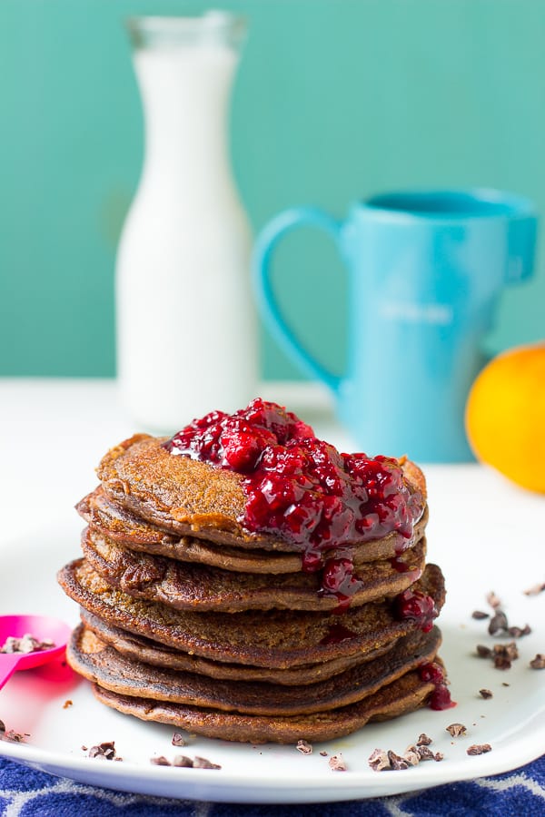 Side shot of chocolate peanut butter pancakes stacked on a white plate.