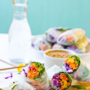 Fresh spring rolls on a wood board with peanut sauce in background
