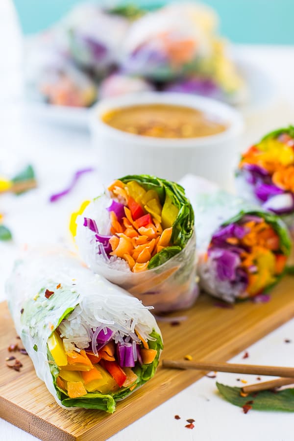 A row of four fresh spring rolls on a wood board.