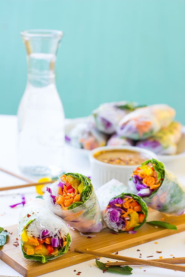 Fresh spring rolls on a wood board with peanut sauce in background