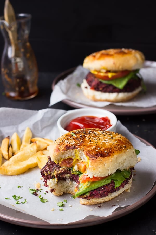 A vegan quinoa beet burger with a bite taken out. 