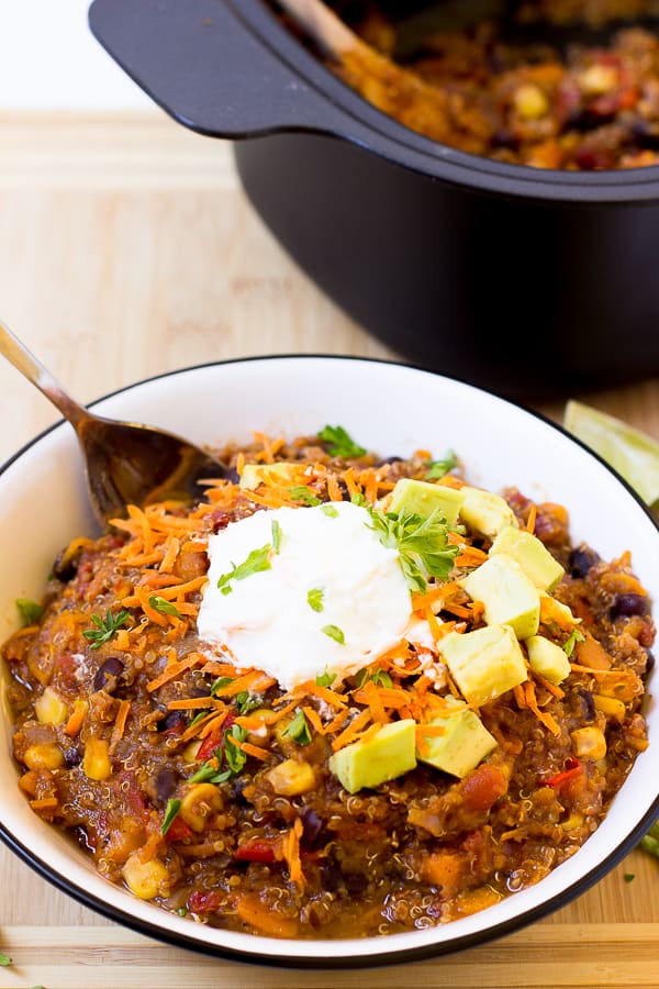 Chili à la patate douce et aux haricots noirs dans un bol blanc avec de la crème sure sur le dessus.