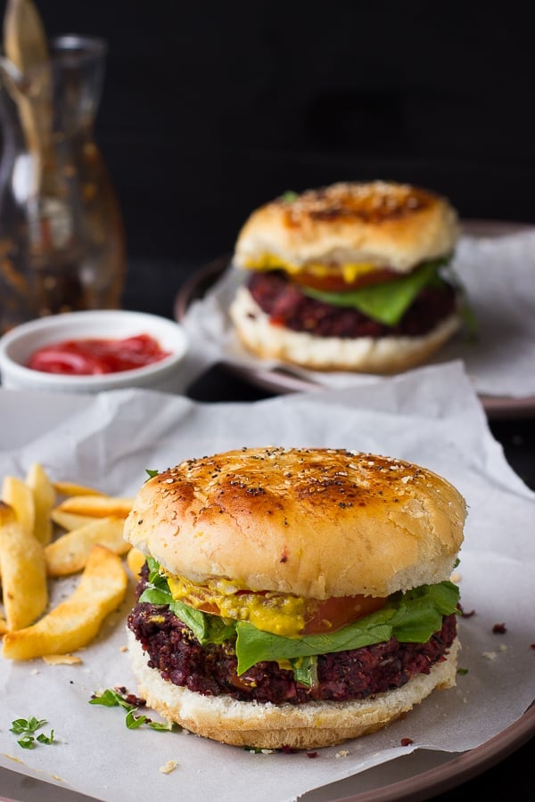 Two vegan quinoa beet burgers on parchment. 