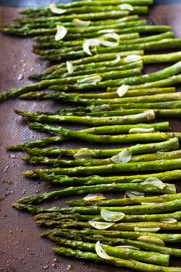 Top down shot of garlic roasted asparagus on a baking tray.