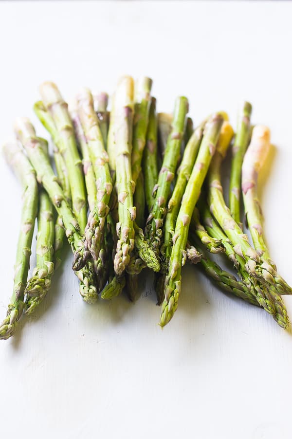 A bunch of raw asparagus on a white table top. 