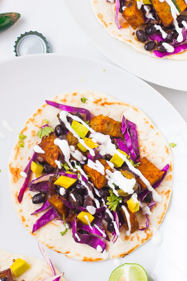 Top down shot of sweet potato and black bean tacos on white plates..