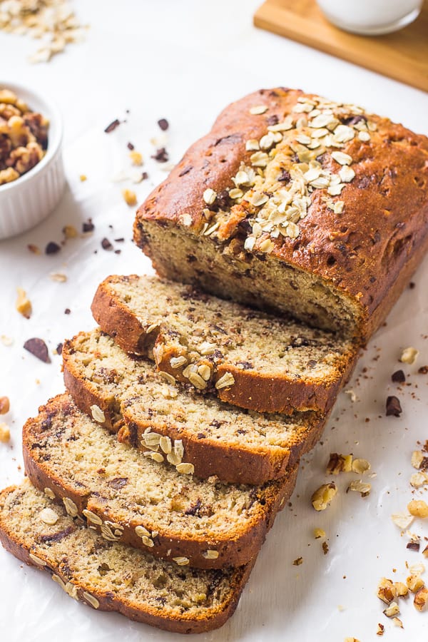 Banana bread slices next to a ramekin of nuts.