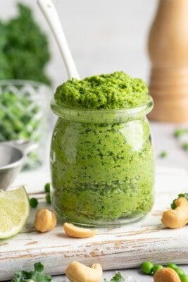 Spoon in jar of cashew pea pesto.