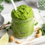 Jar of cashew pea pesto with spoon.