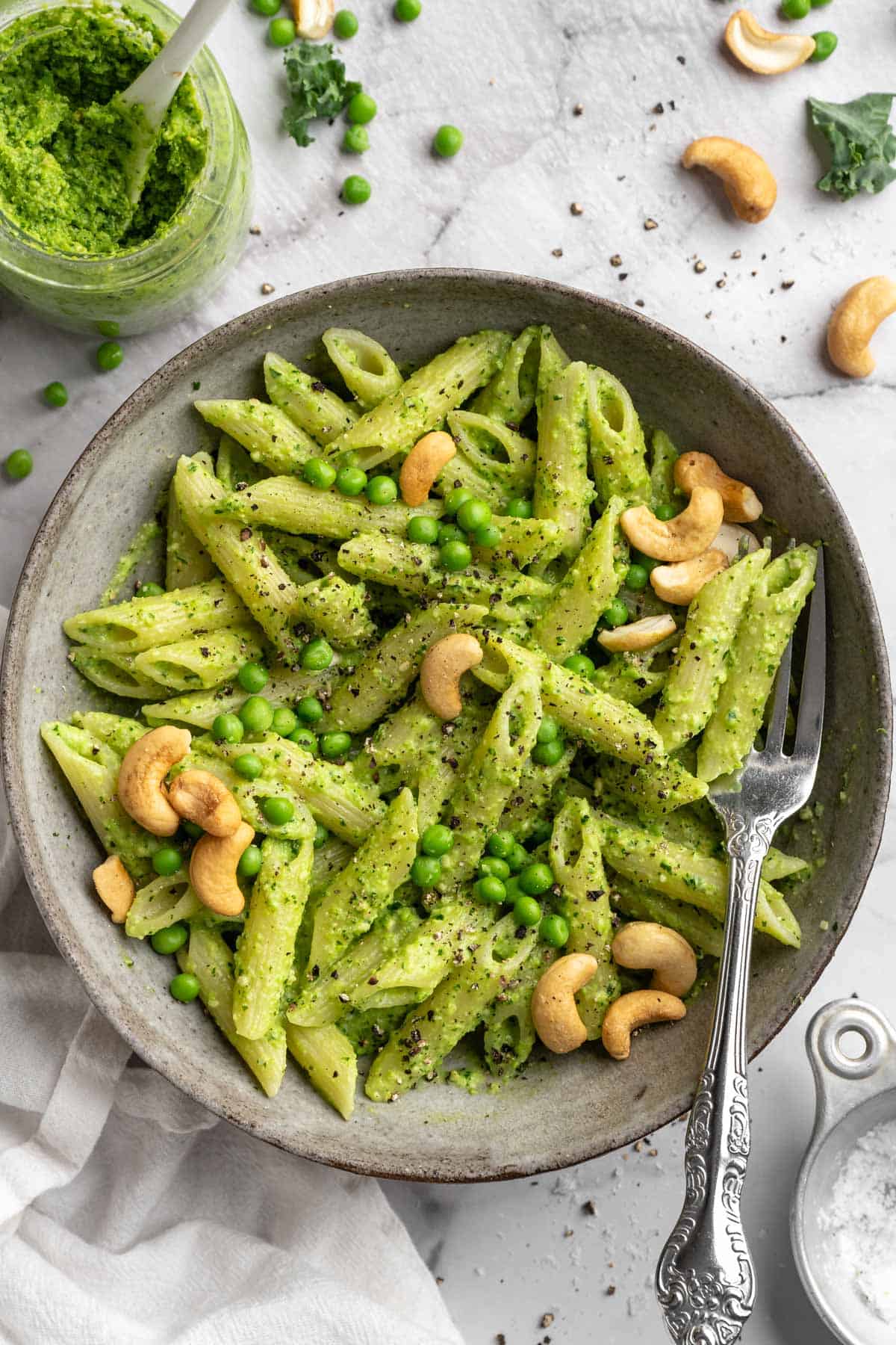 Pasta with cashew pea pesto, whole cashews, and sweet peas.