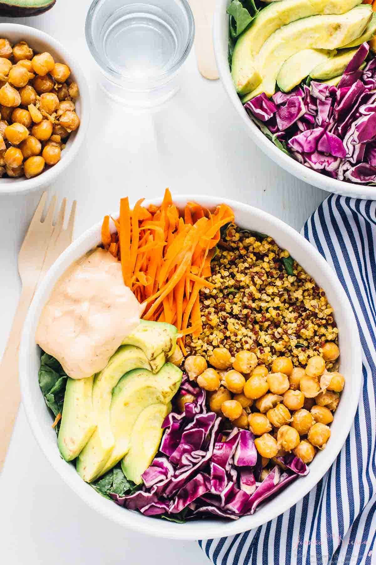 Top down shot of two buddha bowls with a bowl of chickpeas on the side. 