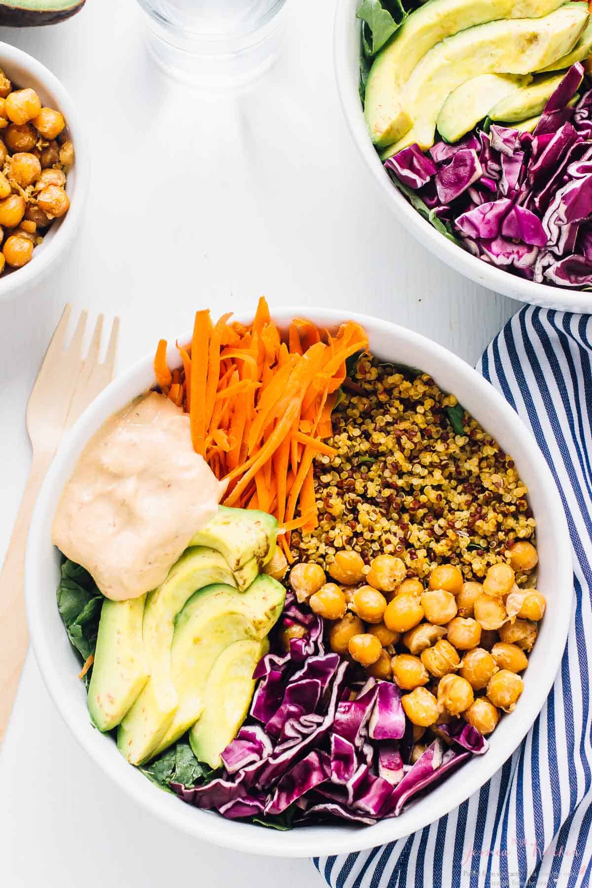 Top down shot of nourish Buddha Bowl on a white table with a wood fork on the side. 