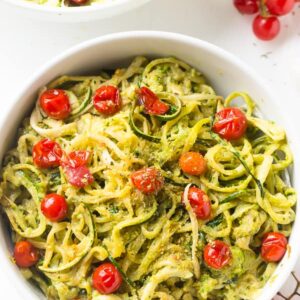 Overhead shot of pesto zucchini noodles in a big white bowl.