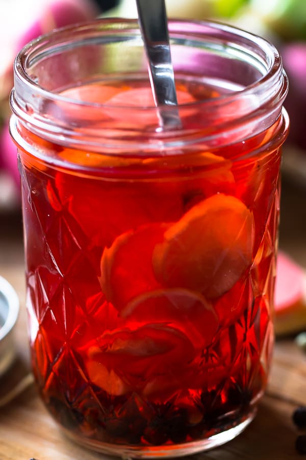 Side on shot of quick pickled radishes in a glass. 