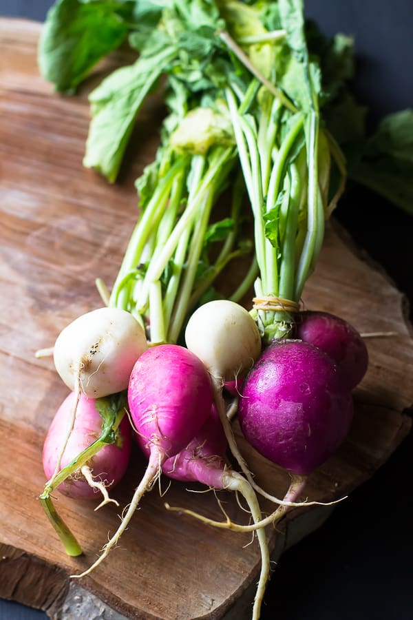 Top down shot of raw radishes on a wood board. 