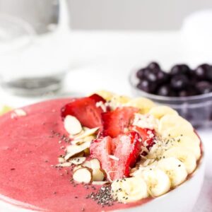 Side on shot strawberry lime coconut smoothie bowl with fresh fruit on top.