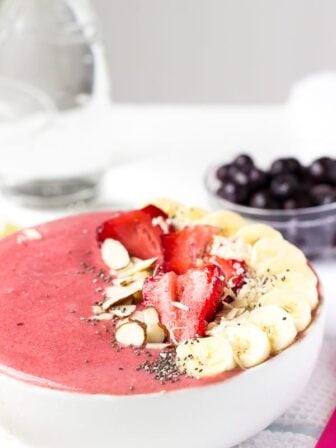 Side on shot strawberry lime coconut smoothie bowl with fresh fruit on top.