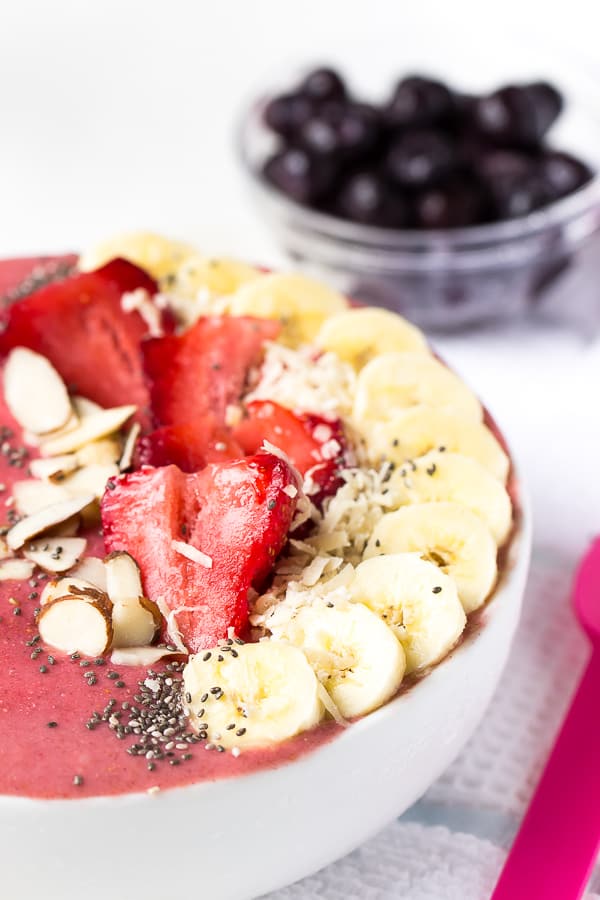 Close up of strawberry lime coconut smoothie bowl with fresh fruit on top. 