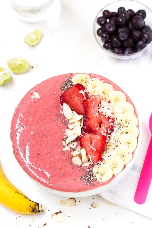 Top down shot of strawberry lime coconut smoothie bowl with fresh fruit.