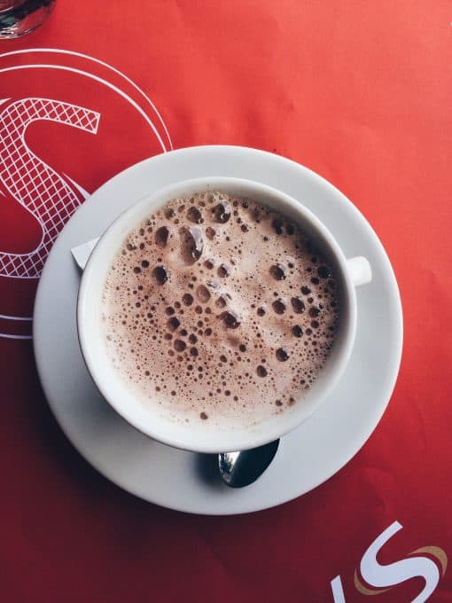 Top down shot of frothy coffee on a red table cloth. 