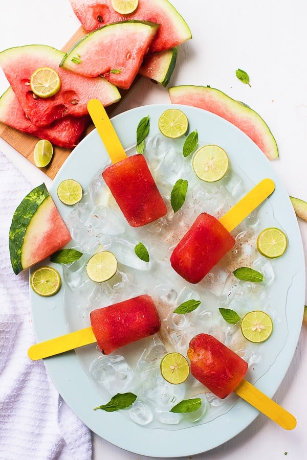 Top down view of watermelon popsicles on a bed of ice. 