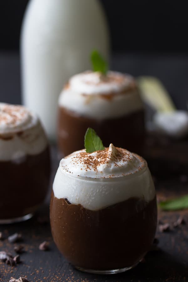 Side shot of three chocolate avocado puddings in glasses.