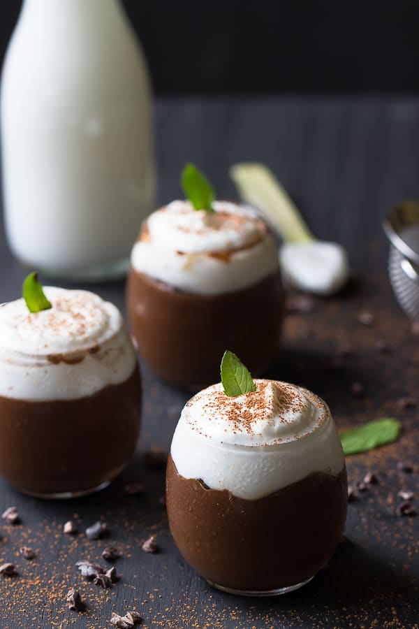 Three cups of chocolate avocado pudding on a black table top. 