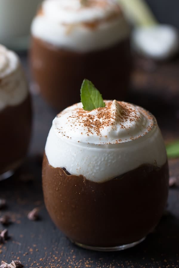  Chocolate avocado pudding in glasses on a dark table top.