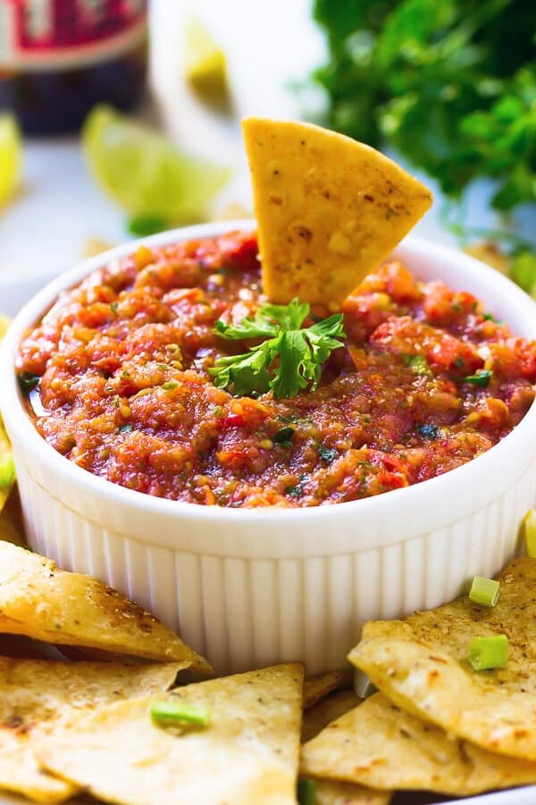 Restaurant style blender salsa in a white ramekin with a chip dipped in it.